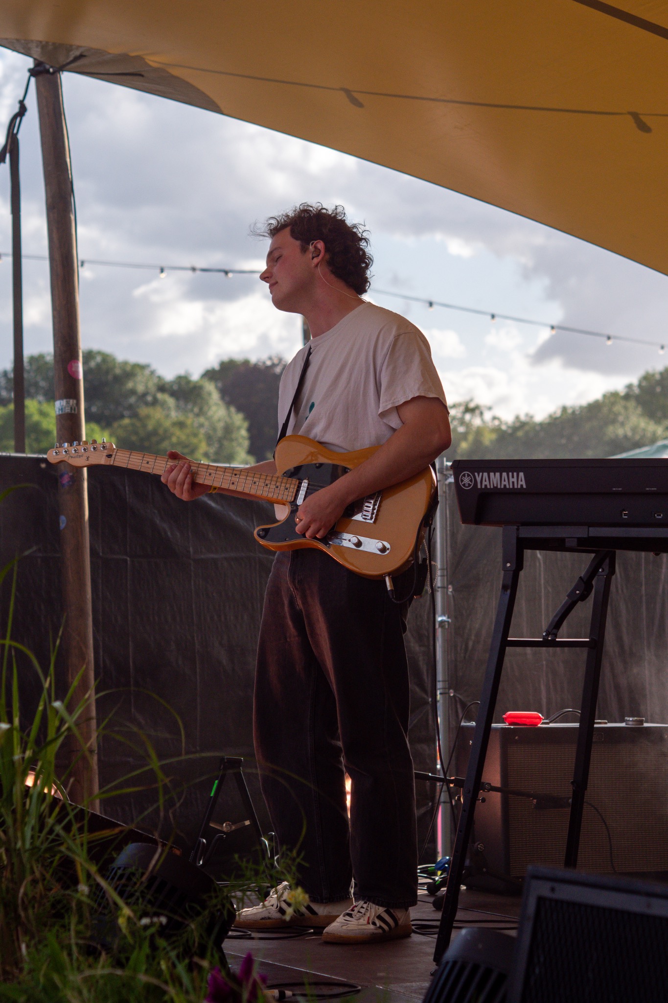 Guitarist standing at the edge of a small outdoor stage.